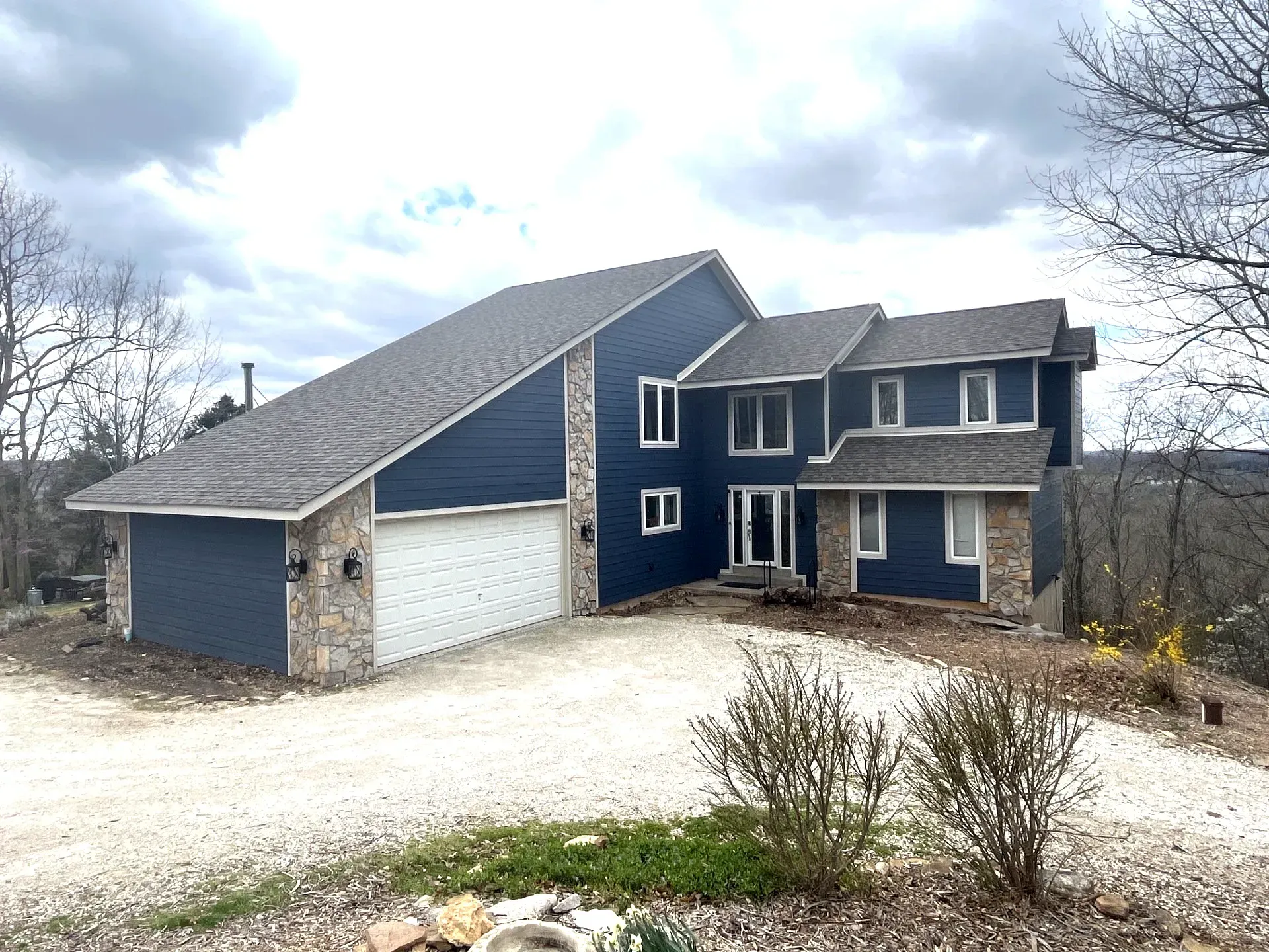 A large blue house with a garage and a fire pit in front of it.