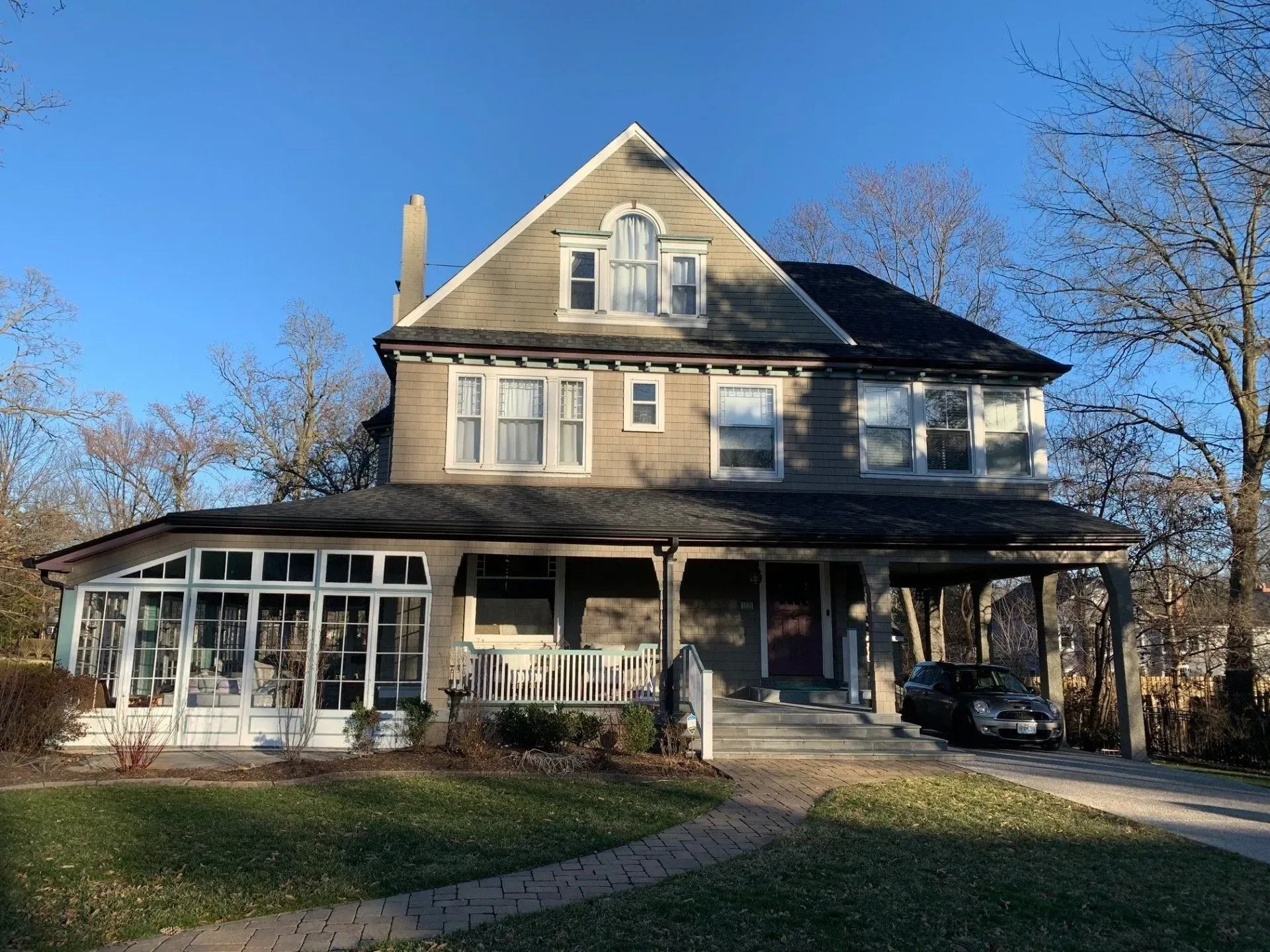 A large house with a large porch and a car parked in front of it.