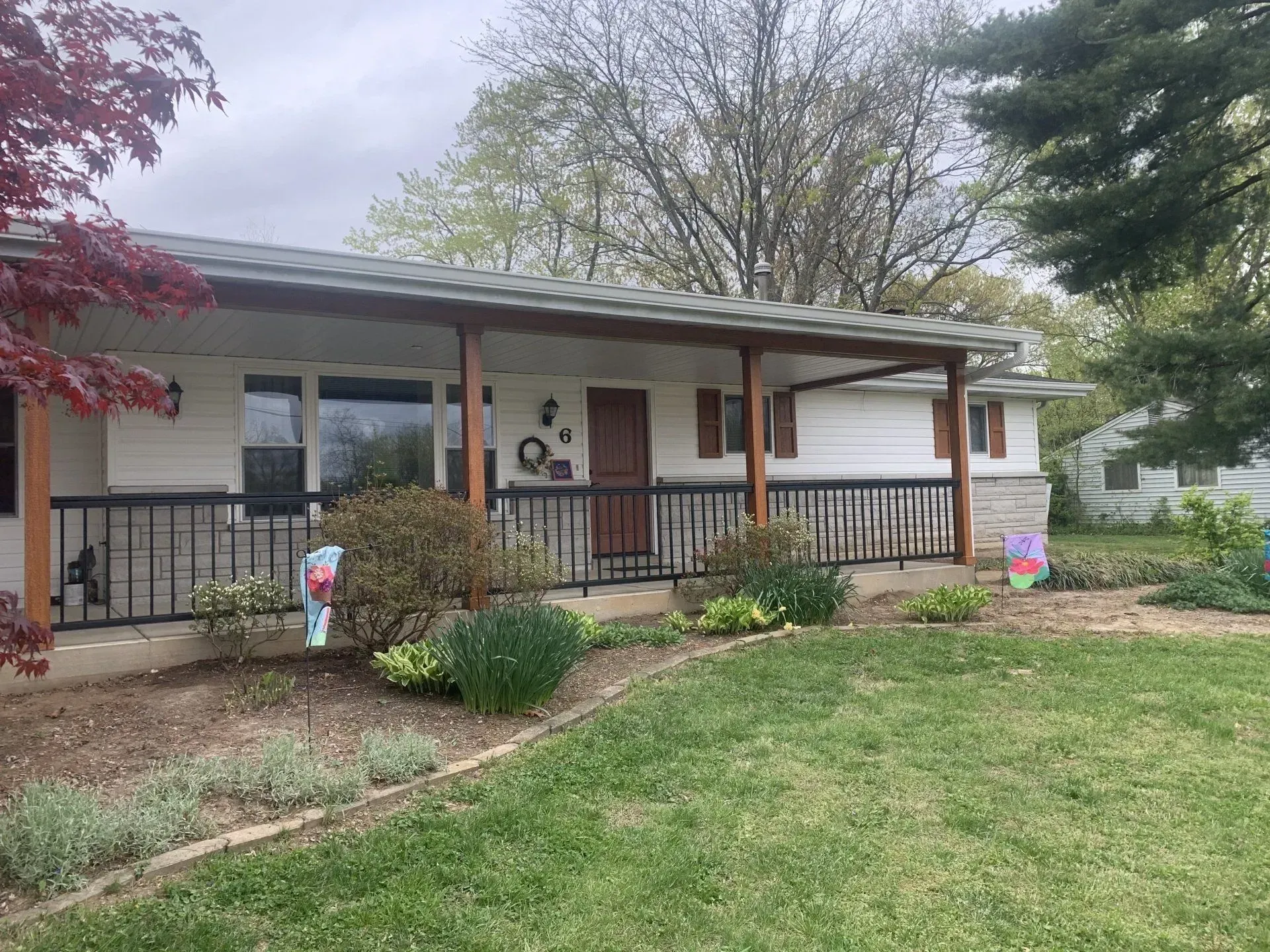 A house with a porch and a fence in front of it.
