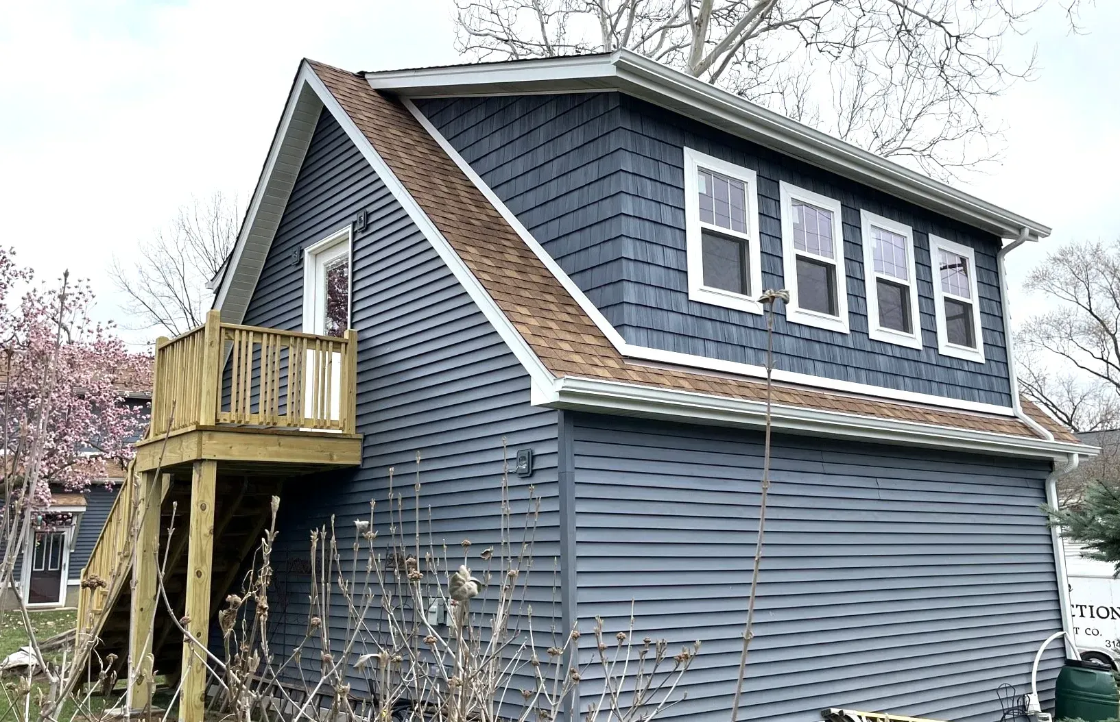 A small house with a deck and stairs on the side of it.
