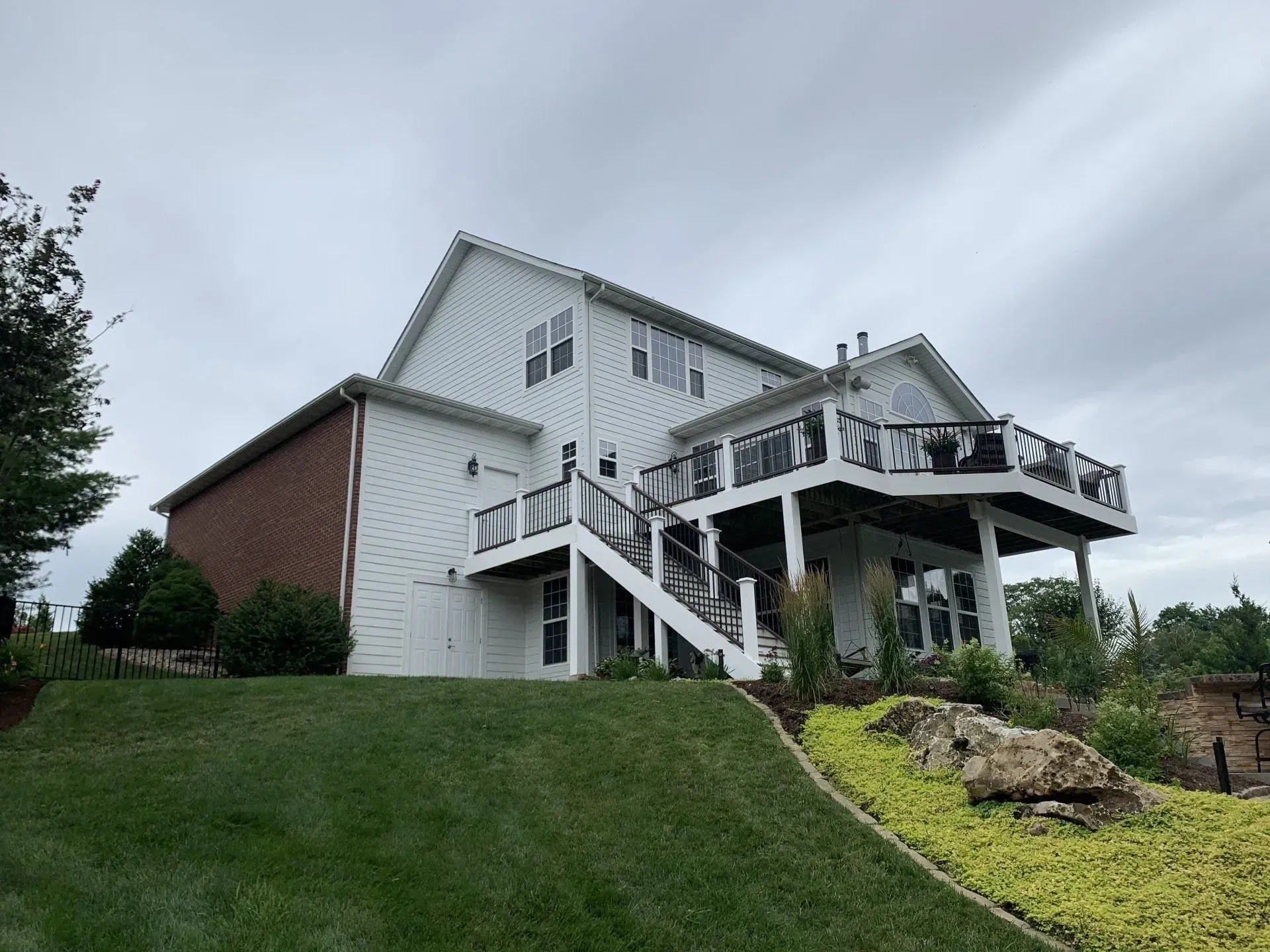A large white house with a large deck and stairs.