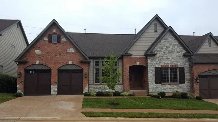 A brick and stone house with three garage doors