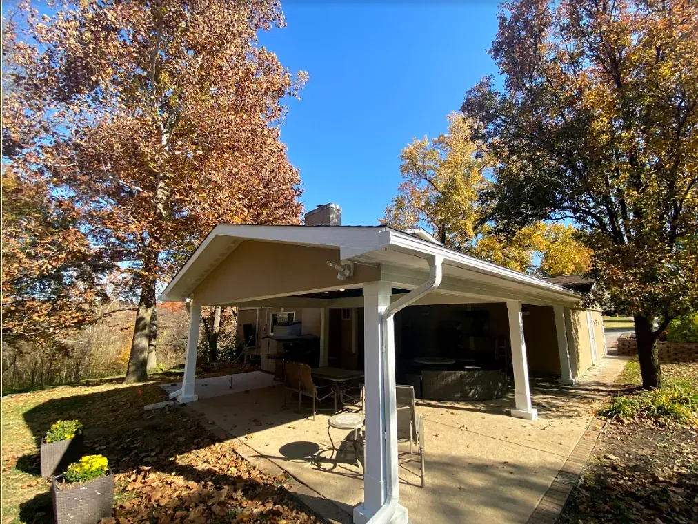 A house with a covered patio and trees in the background