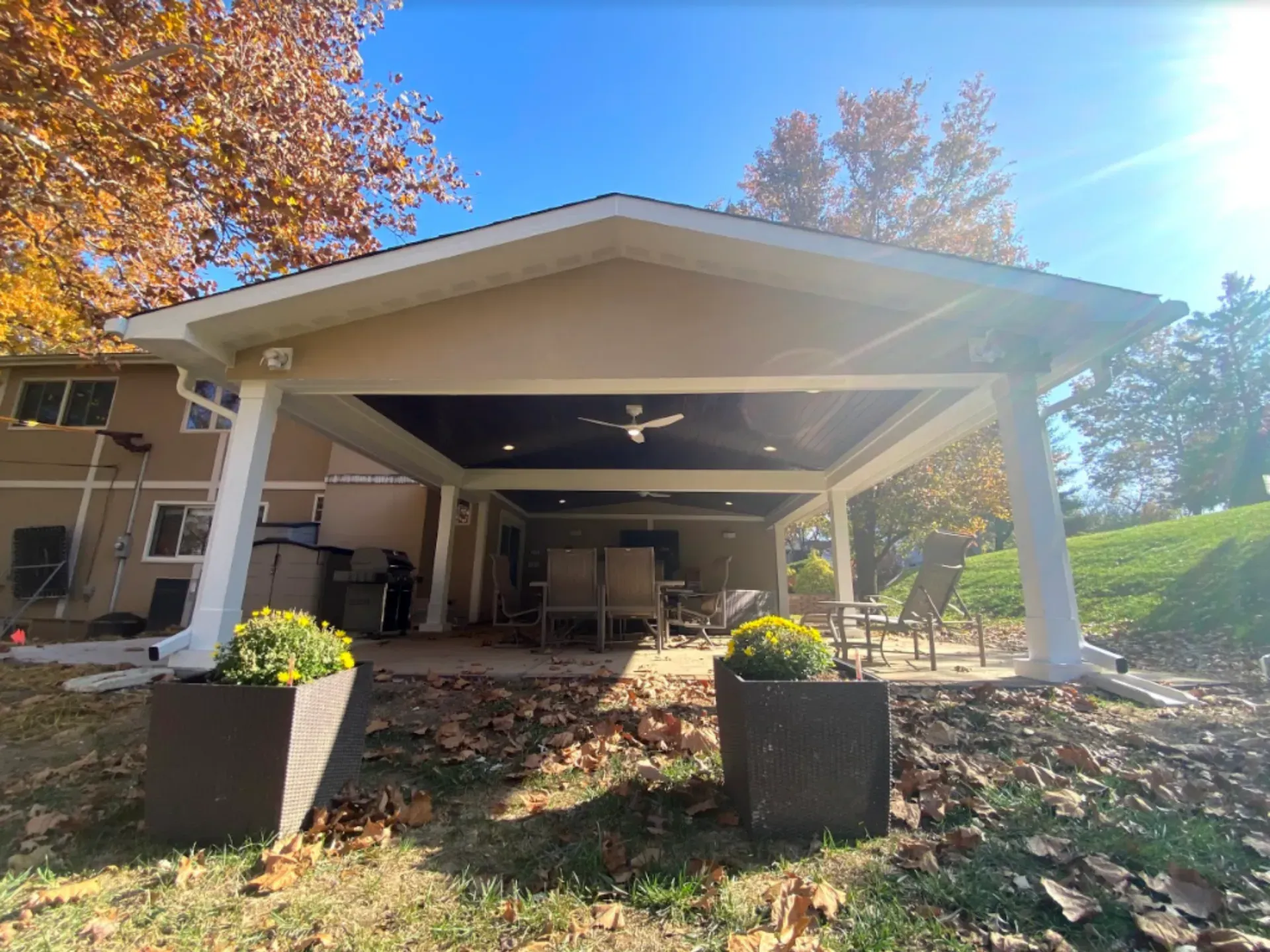 A large covered patio with a ceiling fan in the backyard of a house.