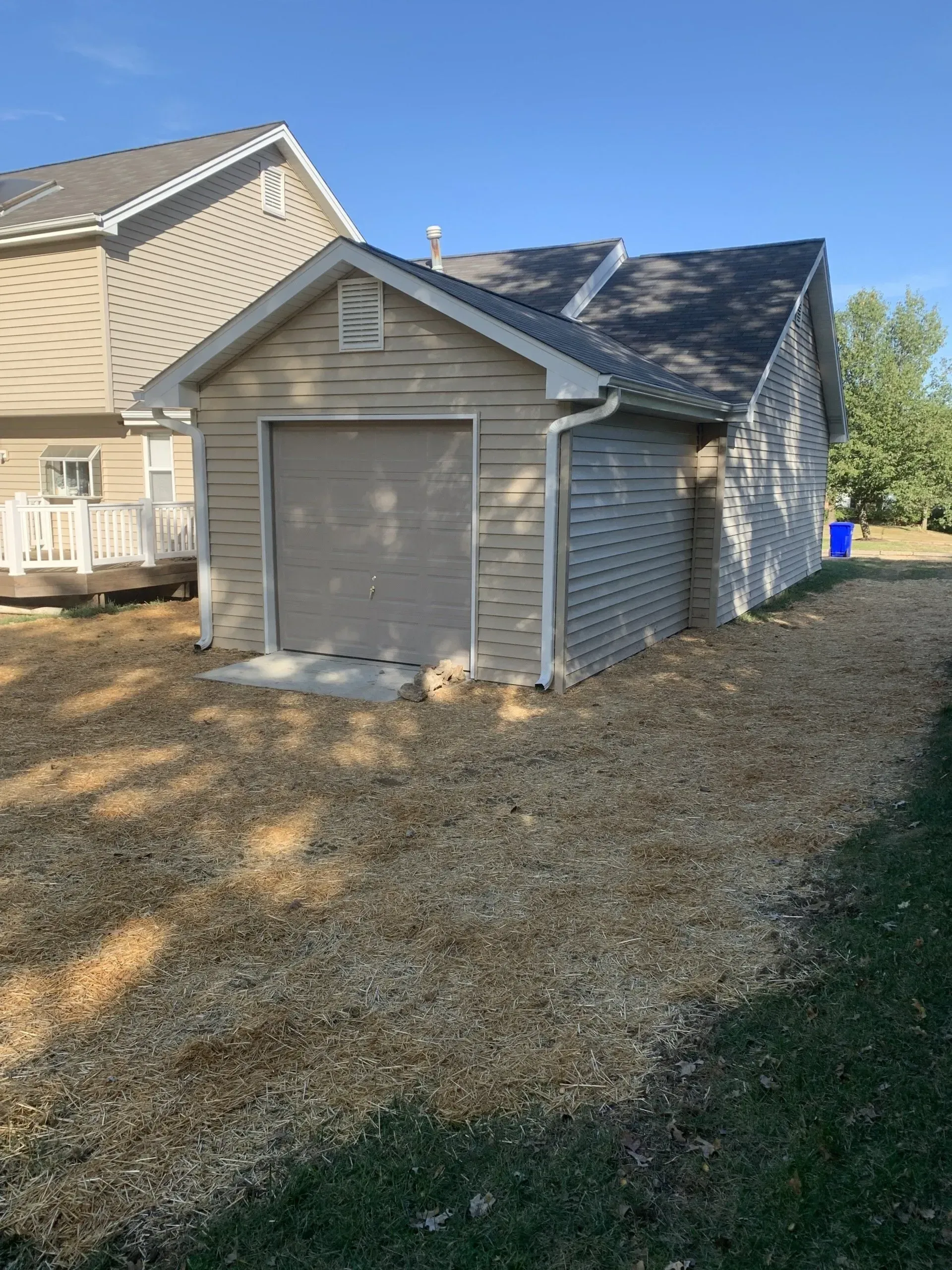 A garage with a garage door is next to a house.
