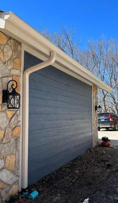 A garage door with a gutter on the side of a house.