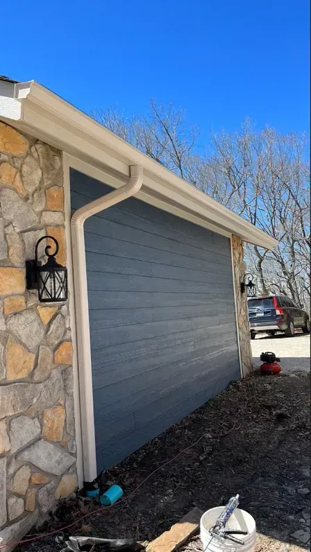 A house with a garage door and a gutter on the side of it.