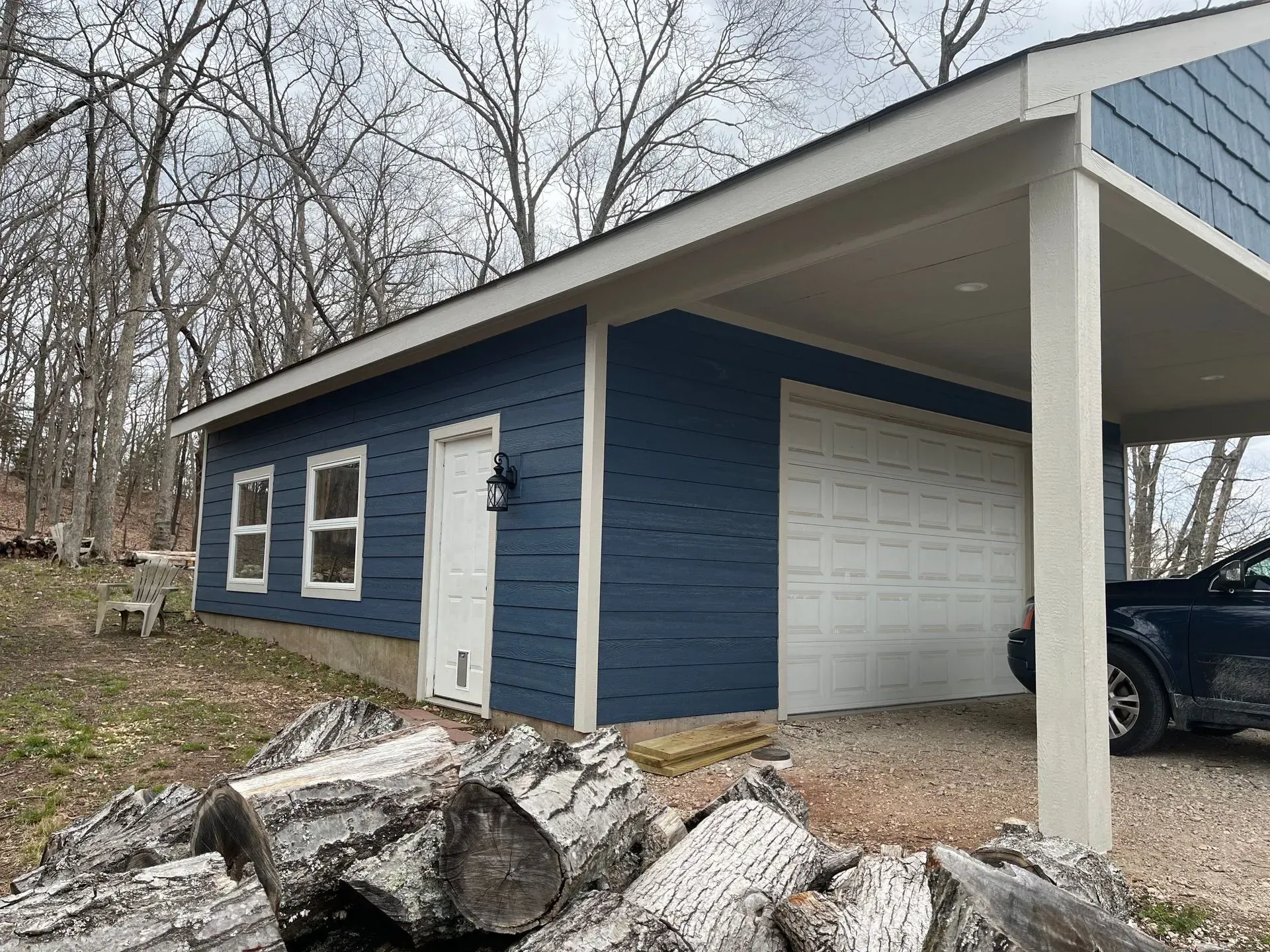 A blue garage with a car parked underneath it.