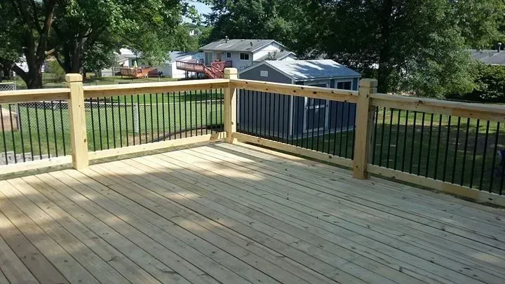 A wooden deck with a metal railing and a shed in the background.