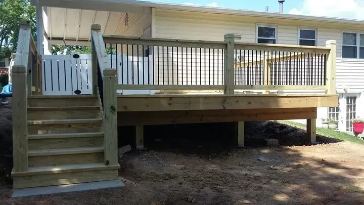 A wooden deck with stairs leading up to it is in front of a house.