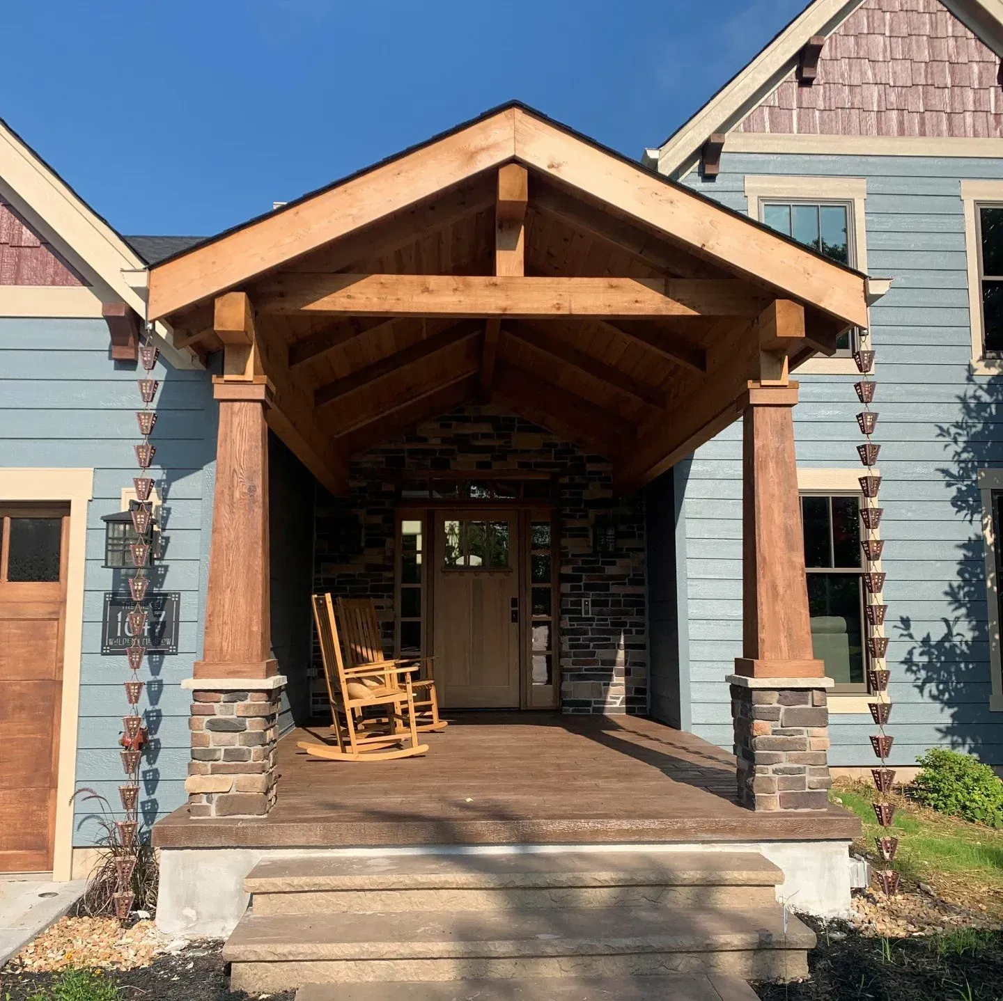 A blue house with a wooden porch and rocking chairs