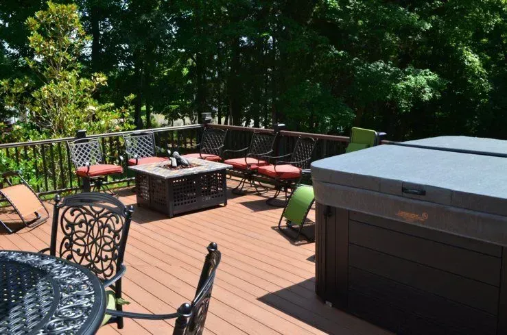 A deck with a table and chairs and a hot tub.
