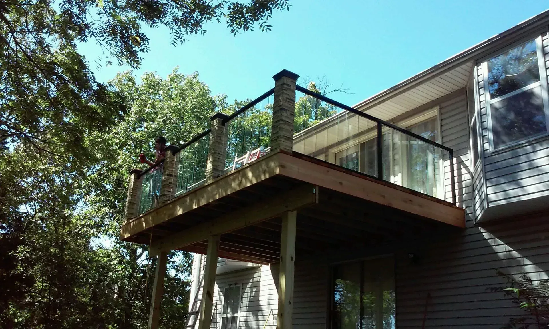 A deck with a glass railing is on the side of a house.
