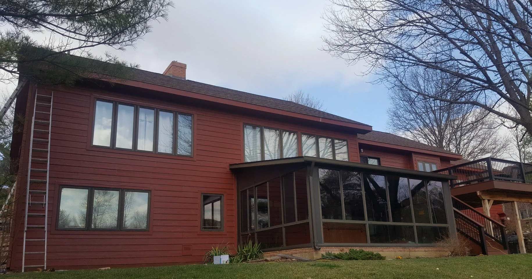 A large red brick house with a screened in porch and stairs.
