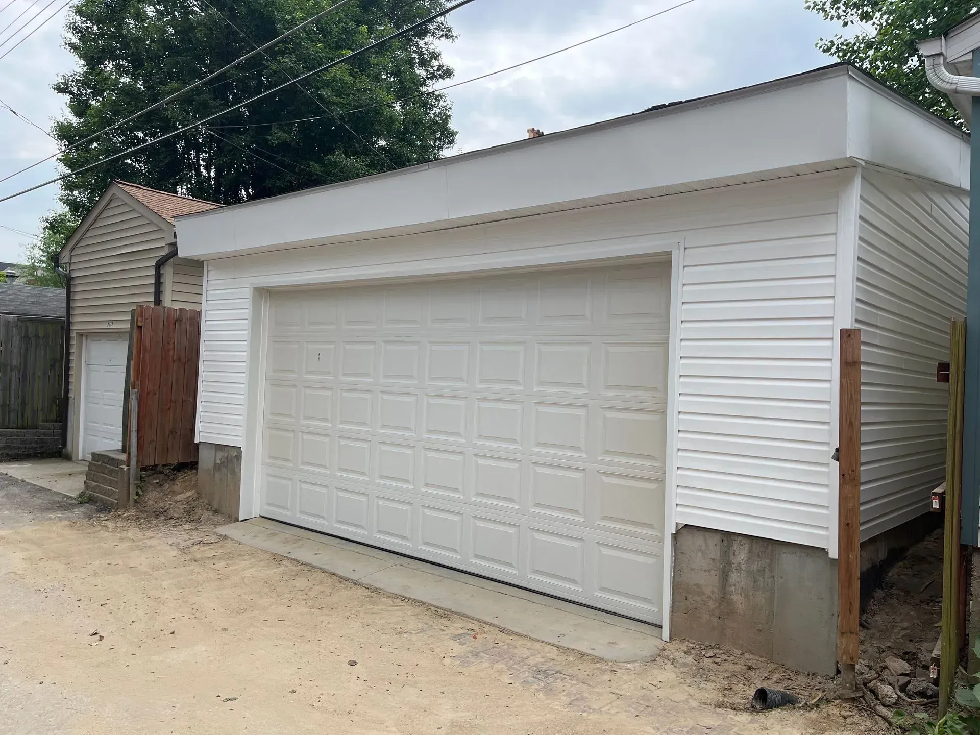 A white garage with a wooden fence in the background