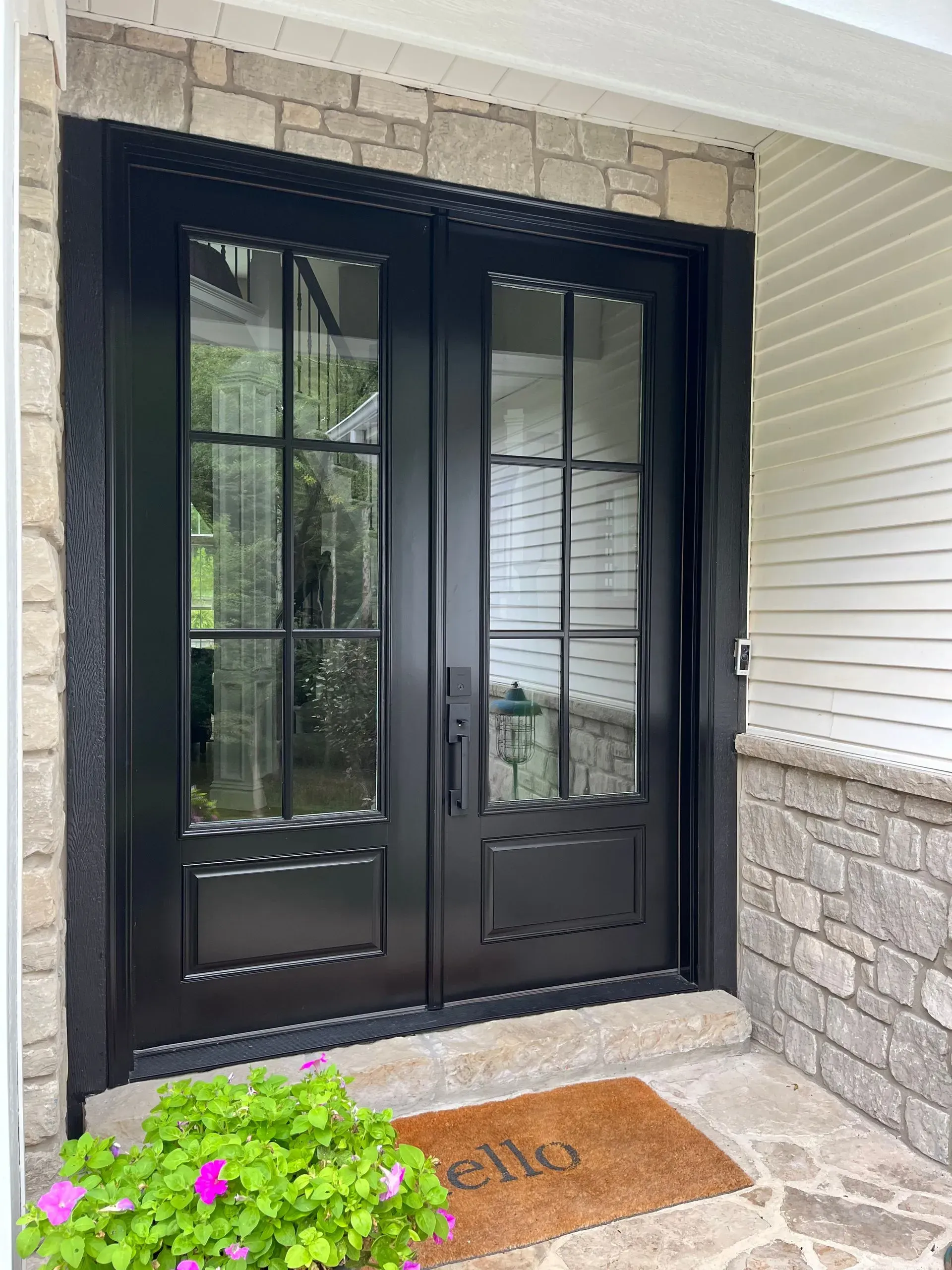 A black door with a welcome mat on the porch of a house.