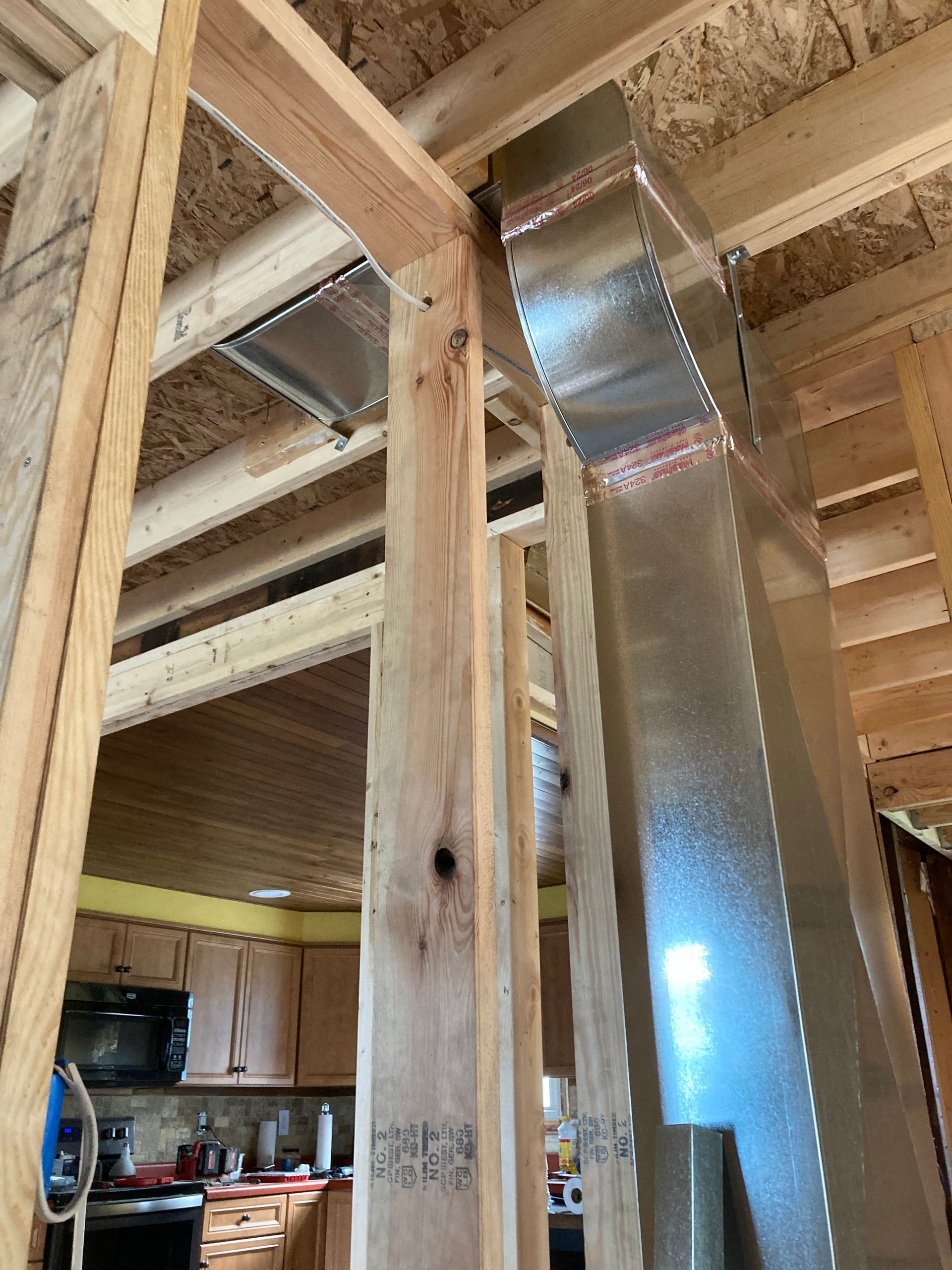 Wooden framing with metal ductwork, inside a building under construction.