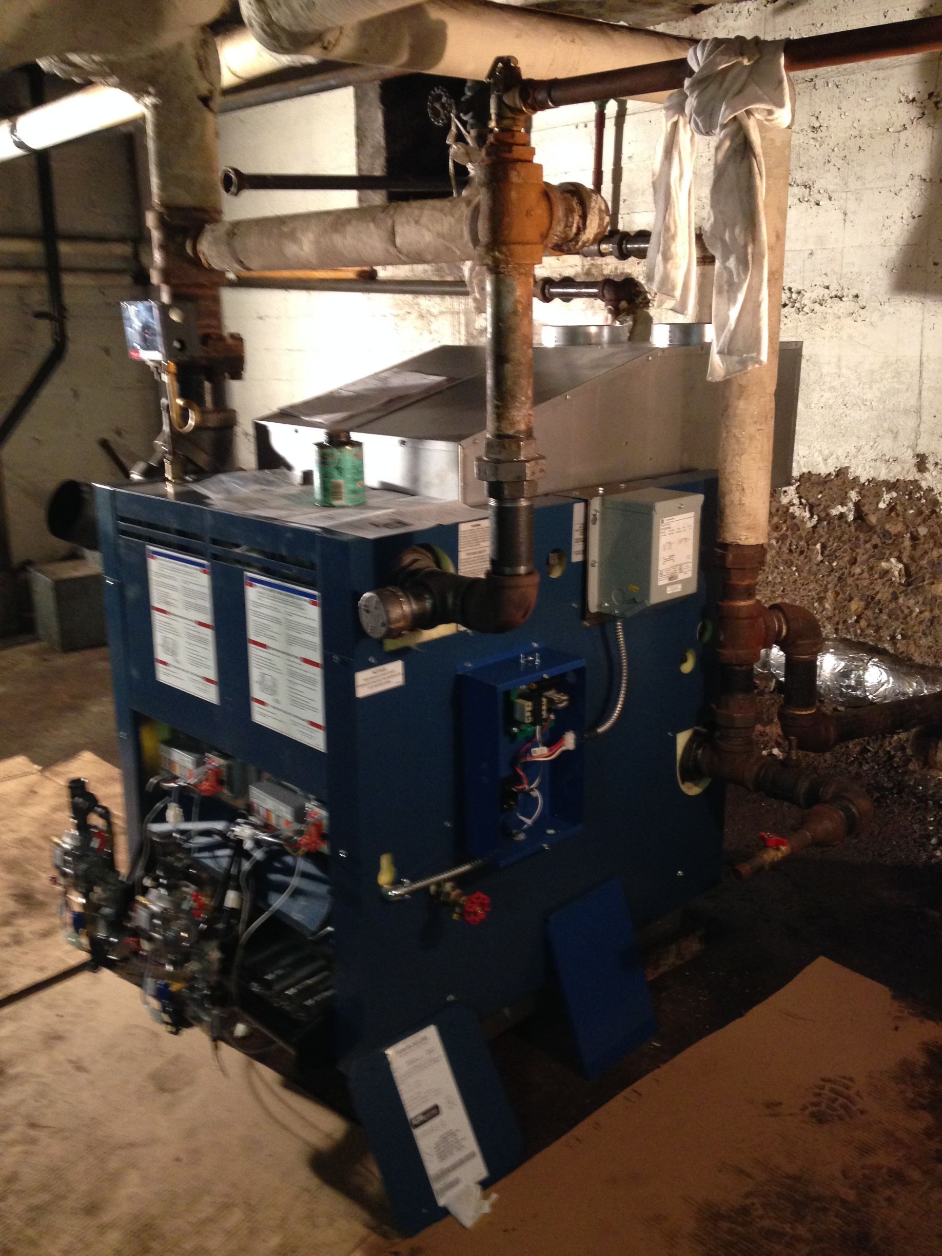 Blue boiler with piping in a basement setting.
