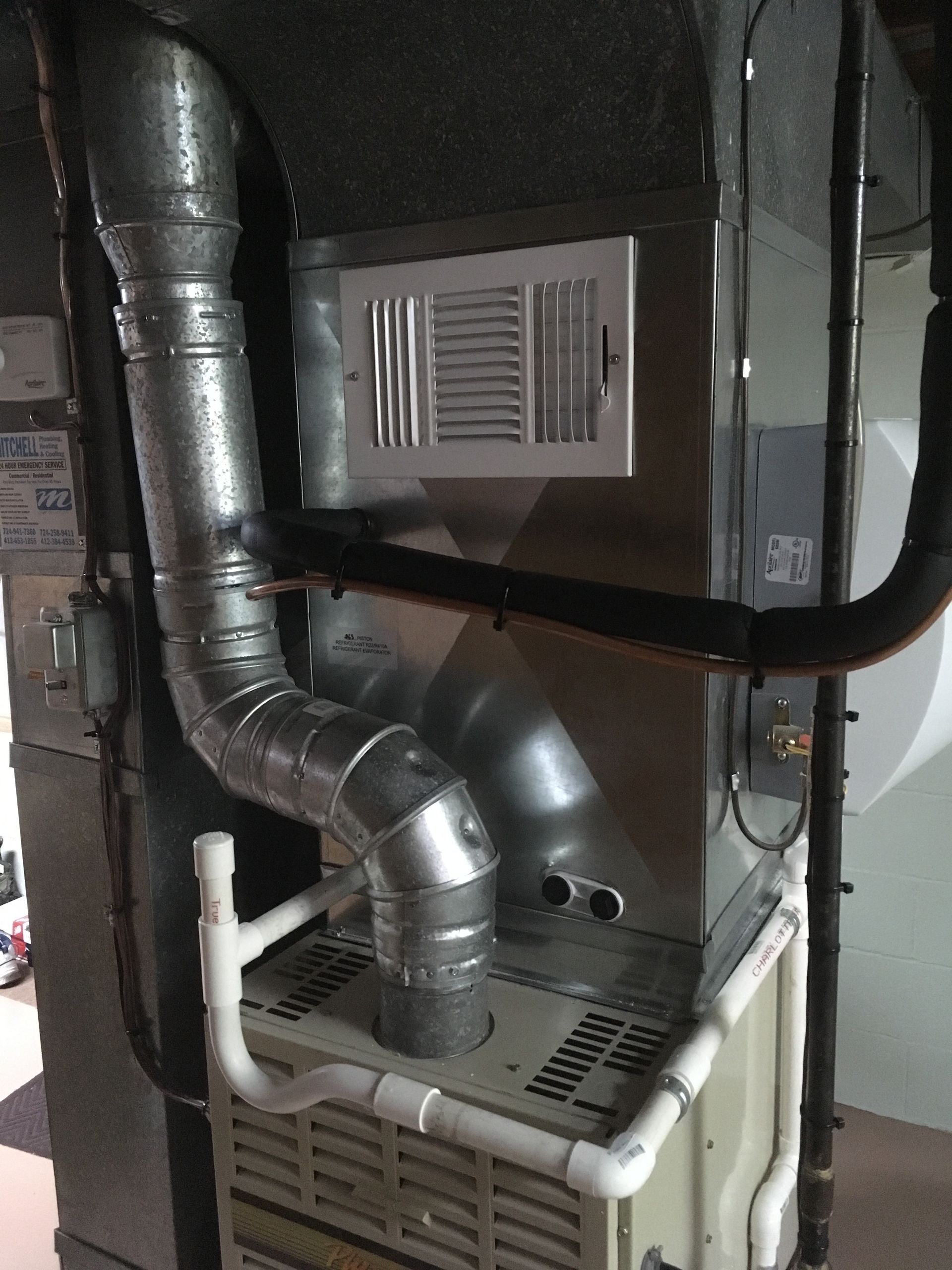 Furnace with connected ductwork and pipes in a basement.