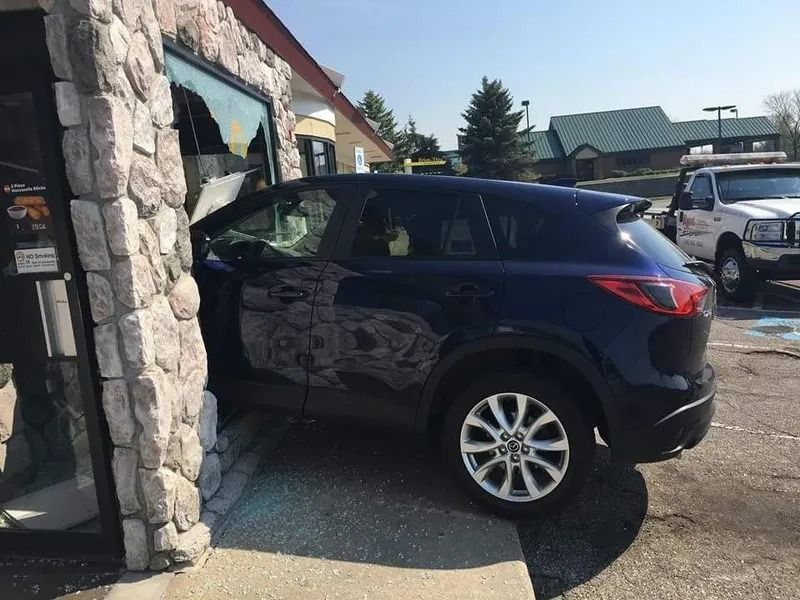 Dark SUV parked beside a stone building on a sunny day.