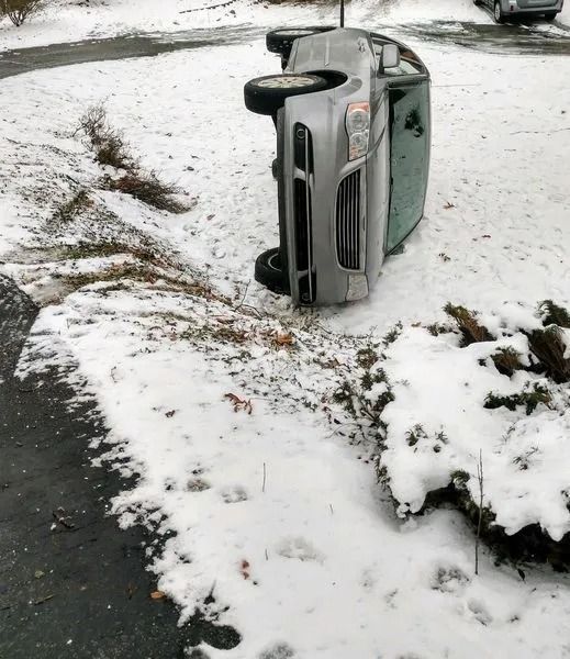 Overturned silver car on a snowy roadside ditch