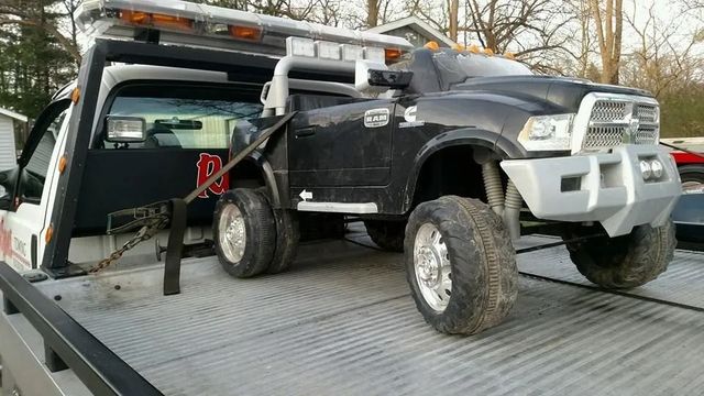 Black off-road truck on a flatbed trailer being winched up with a tow truck in a snowy setting