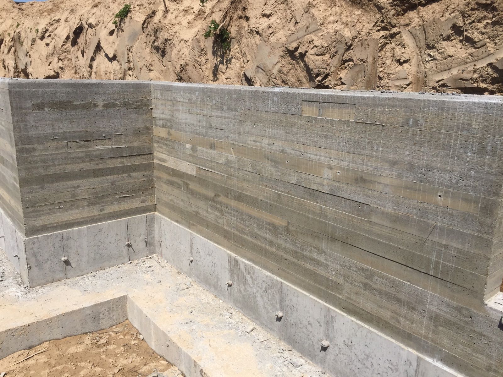 A concrete wall is being built on top of a dirt hill