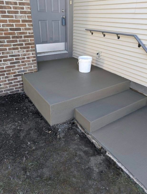 A bucket is sitting on a porch next to a brick building.