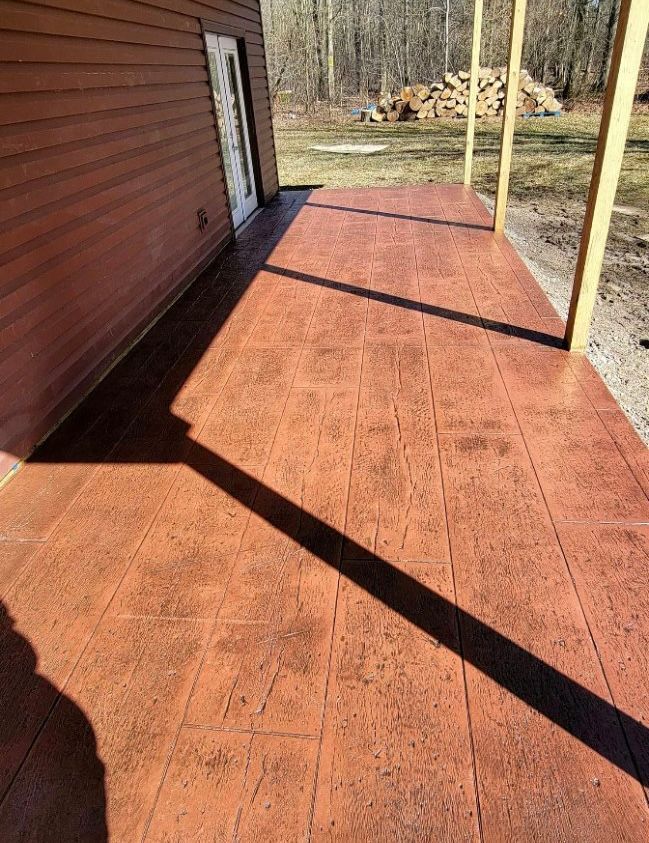 A red concrete porch with a wooden house in the background.