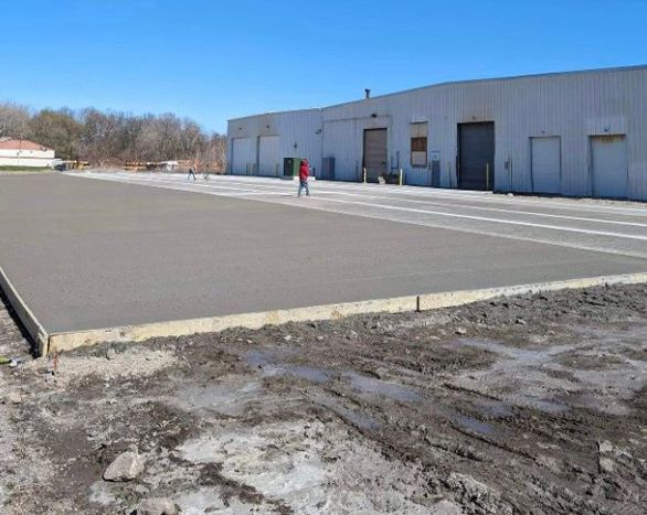 A concrete driveway is being built in front of a large building.