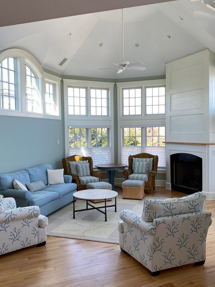 A living room with a blue couch and white chairs