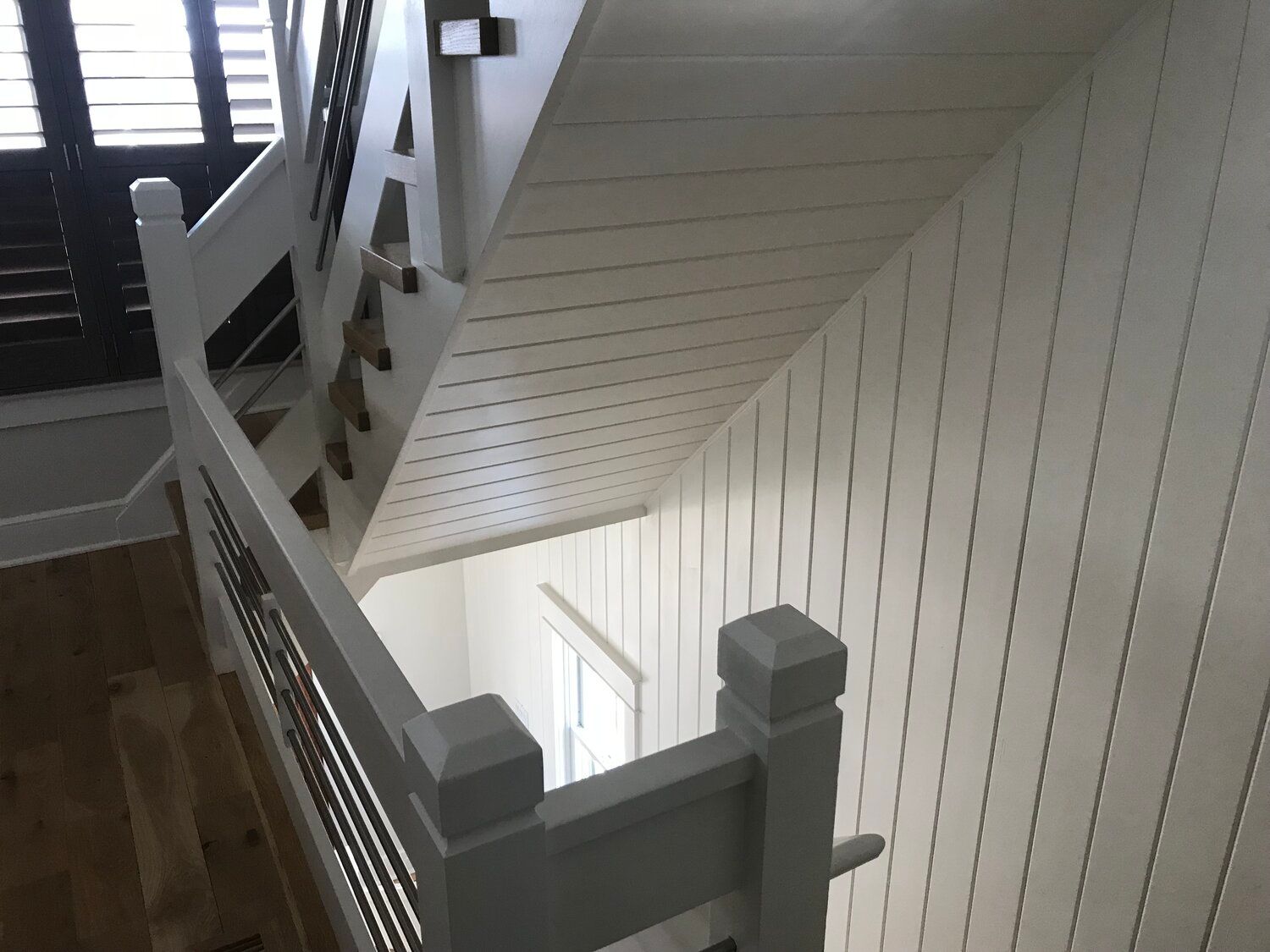 A staircase with white walls and a gray railing