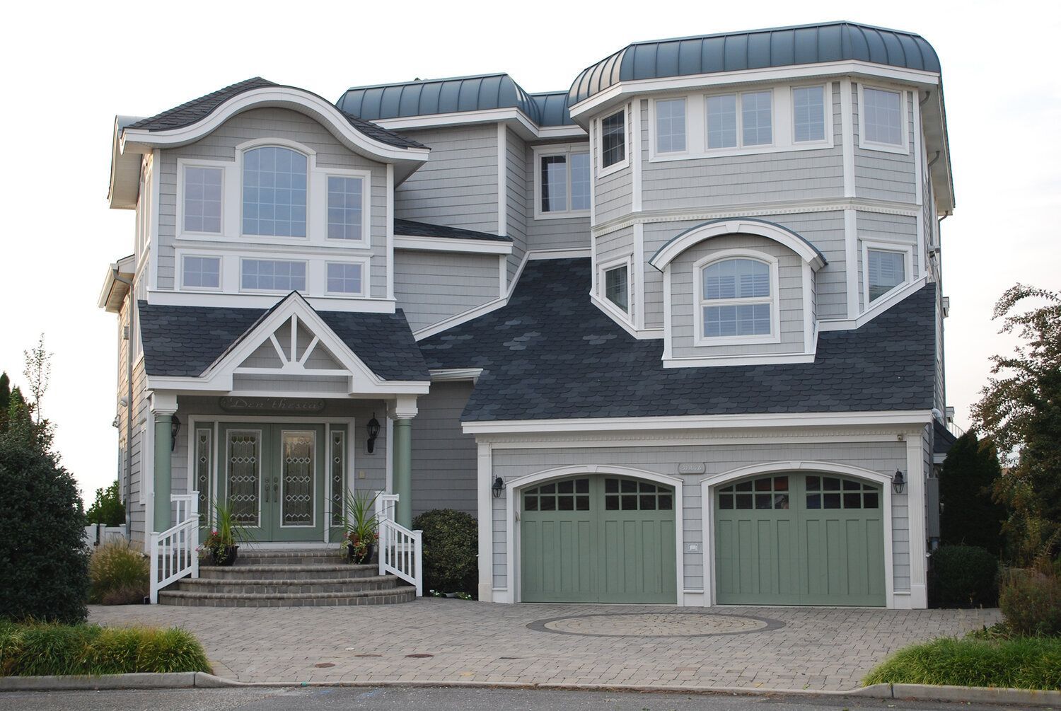 A large house with a blue roof and green garage doors