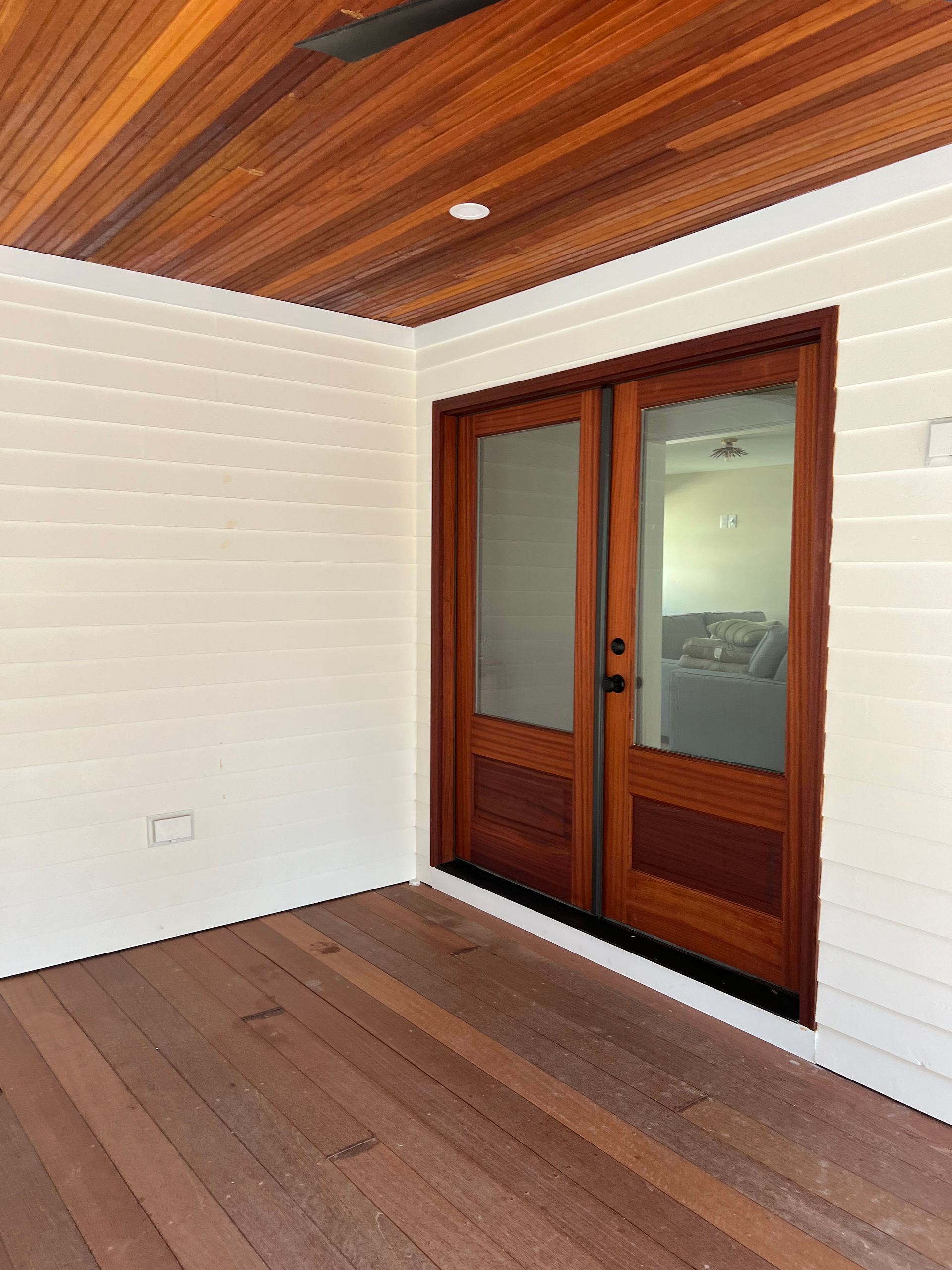 A patio with wooden floors and sliding glass doors leading to a living room.