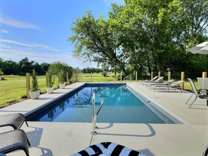 Outdoor swimming pool with lounge chairs and trees on a sunny day