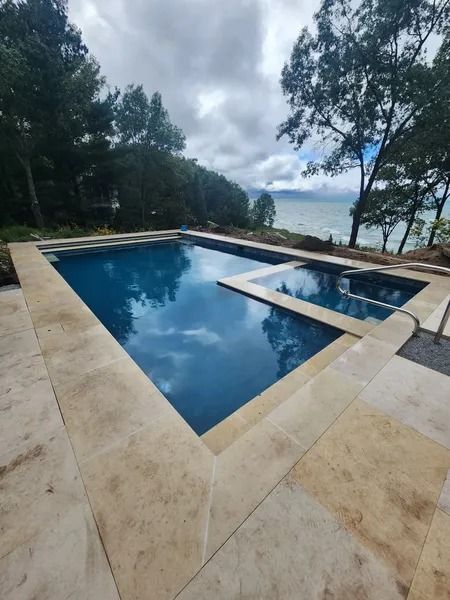 Infinity pool overlooking the ocean, framed by trees and a stone deck.