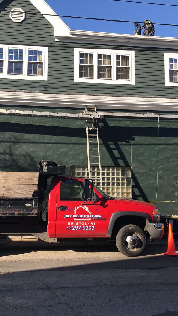 A red truck is parked in front of a green building