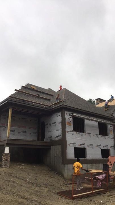 A man is standing on the roof of a house under construction.