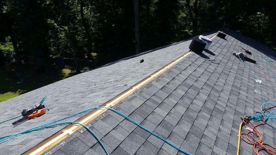A roof is being repaired with tools and a hose.