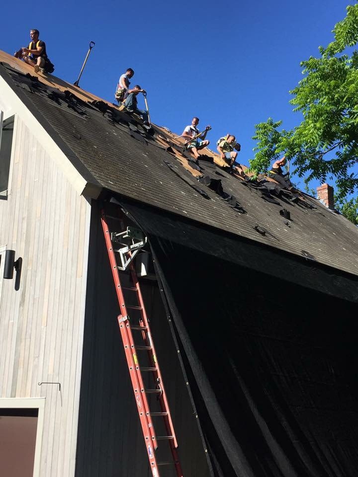 A group of men are working on the roof of a house