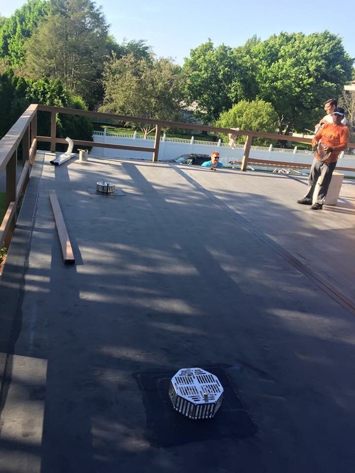 A man is standing on a roof with a drain on it.