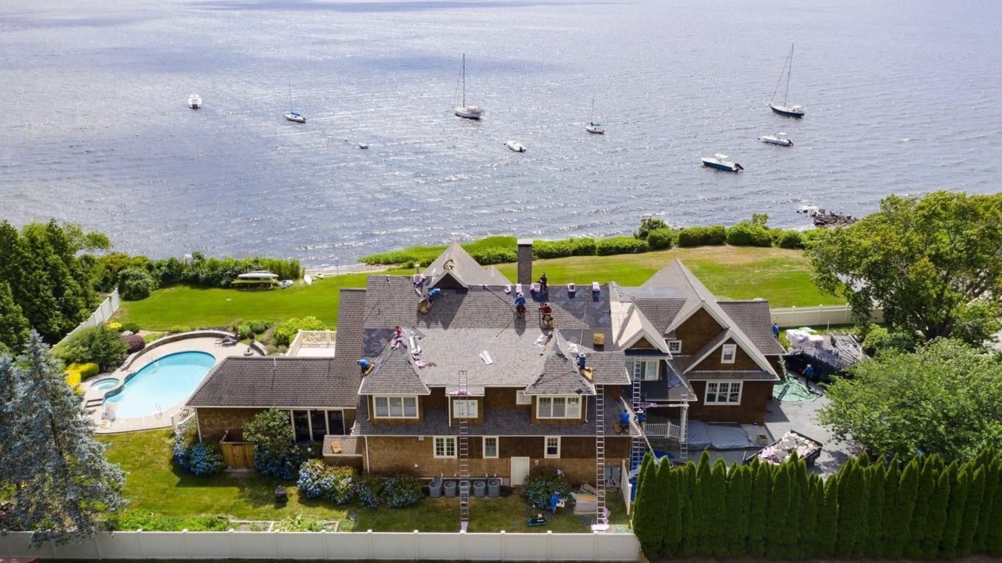 An aerial view of a large house next to a body of water