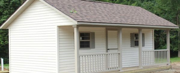 A small white house with a porch and shutters.
