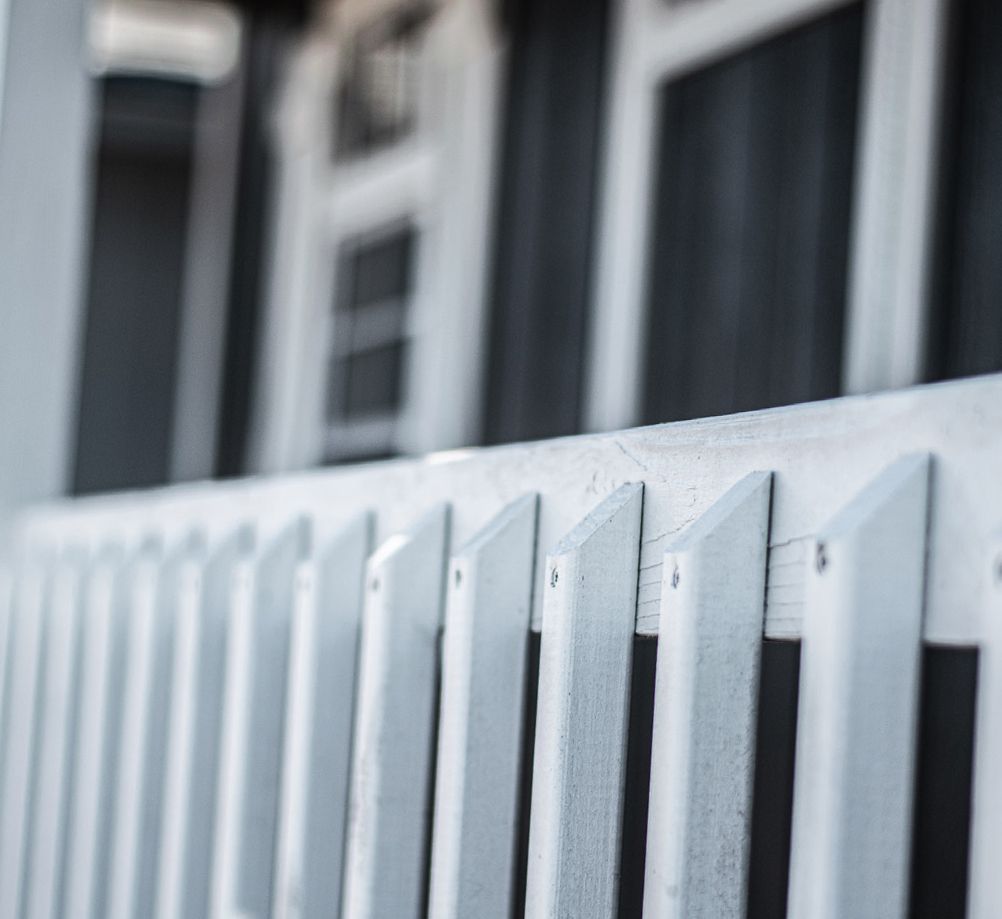 A white fence with a black building in the background
