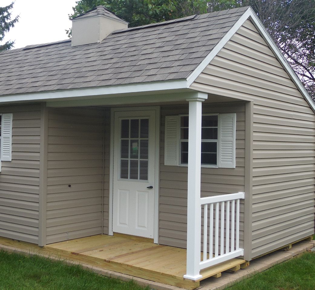 A small house with a porch and shutters on the windows
