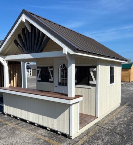 A small white building with a brown roof and a bar