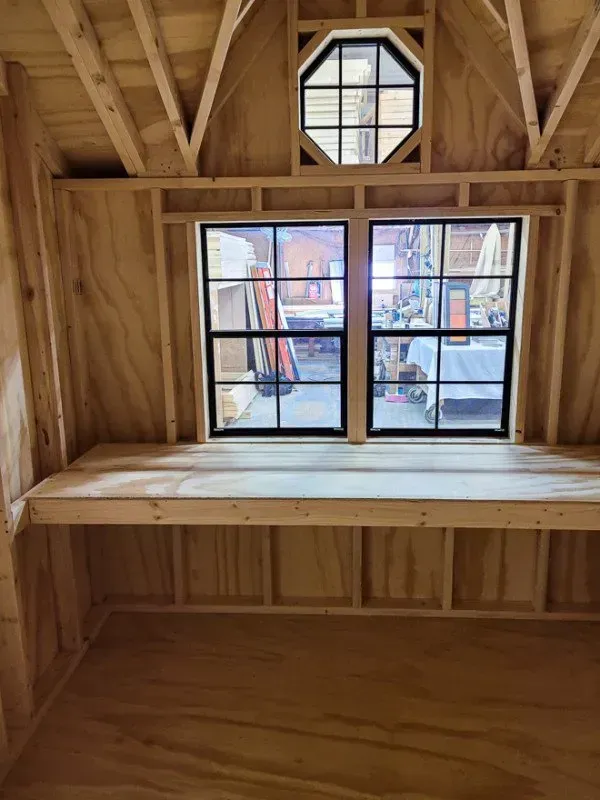 A wooden room with a window and a wooden desk.