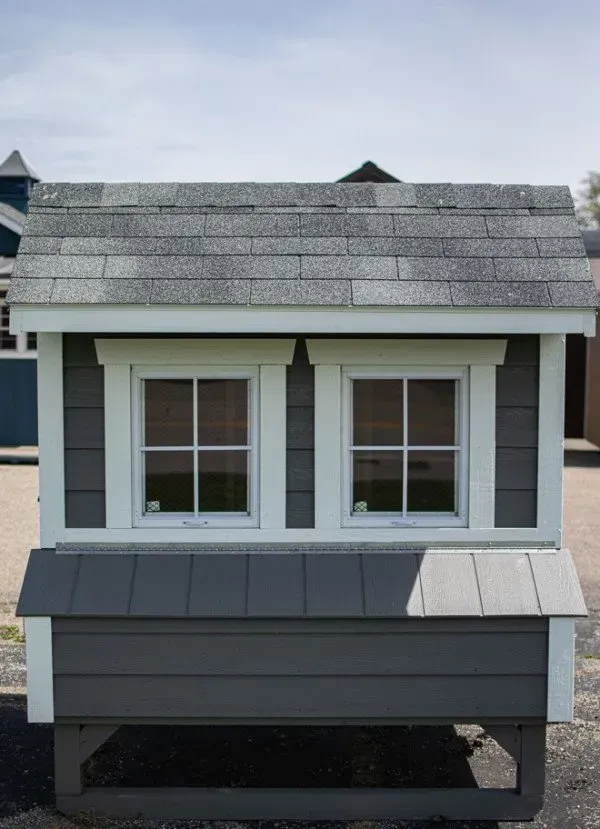 A small chicken coop with two windows and a roof