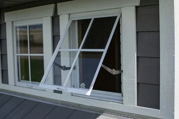 A white window is open on a gray house