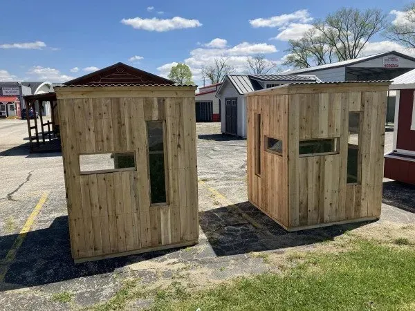 Two wooden houses are sitting next to each other in a parking lot.